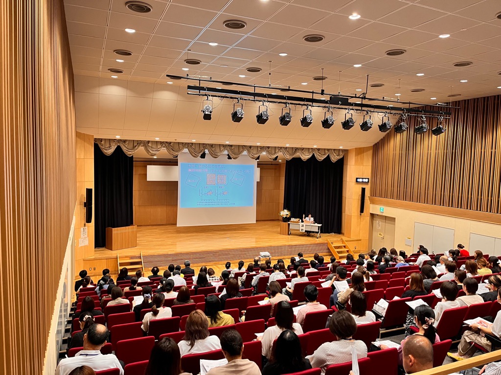 コスモスプラザで行われた家庭教育講演会の様子。約140人の参加者の後ろからステージ、講師の先生を撮った写真