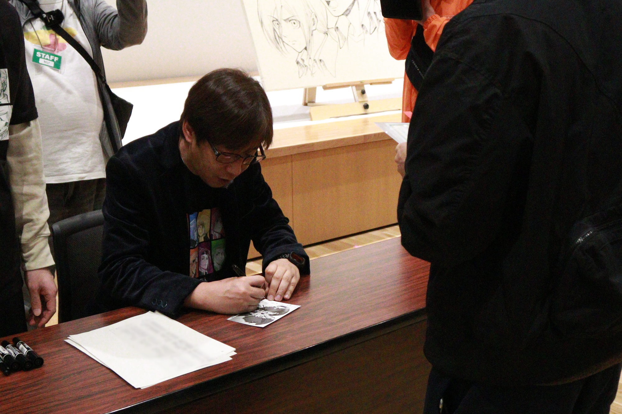 浅野先生がサイン会に当たった人へポストカードにサインをする様子