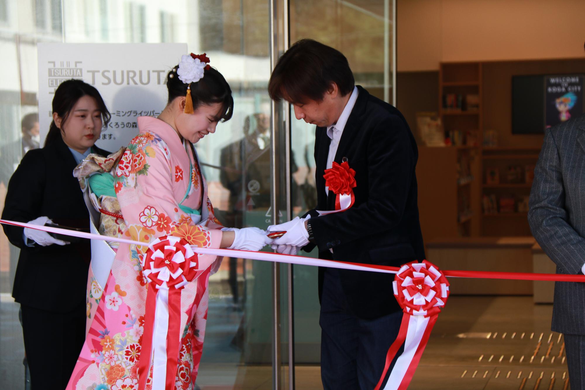 竣工式でテープカットのハサミを渡してもらう様子